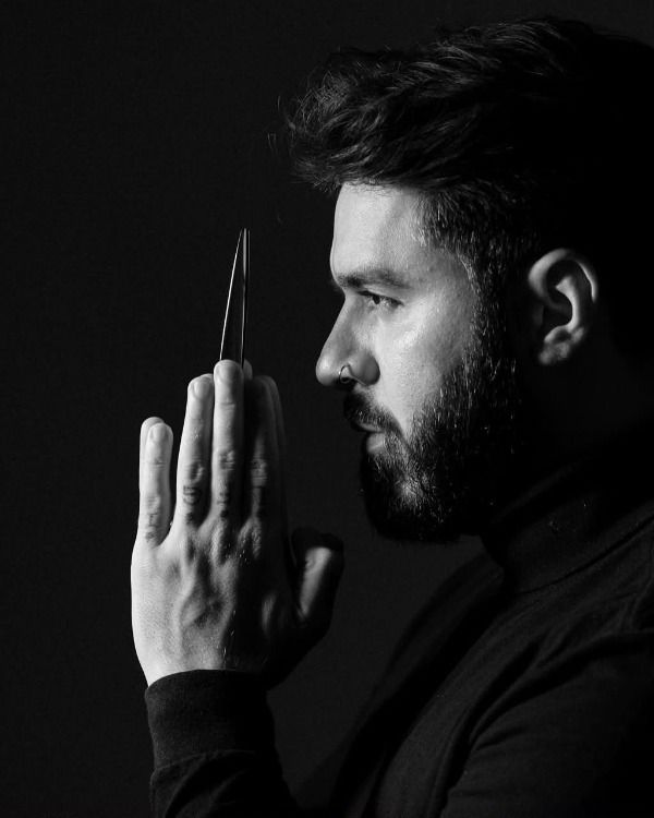Bruno Caldas segurando uma tesoura, em retrato preto e branco