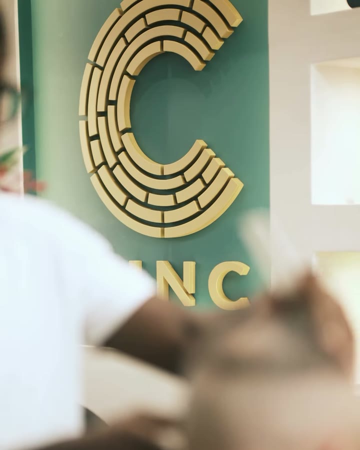 O C dourado da CINC na parede verde-menta, com um corte em andamento à frente